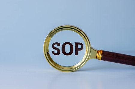 Magnifying glass with acronym SOP (Standard Operating Procedure) isolated on yellow backgroundの写真素材