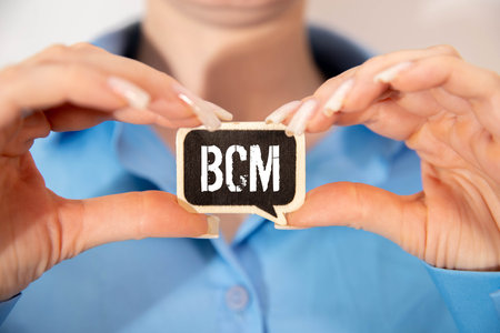 bcm, business continuity management text on cube blocks in businessman hands, white background