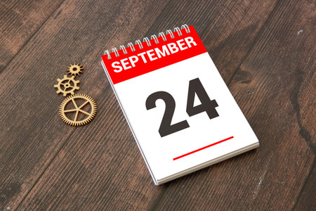Wooden calendar with the date September 24. Monthly calendar for planning and management concept with alarm clock on wooden backgroundの写真素材