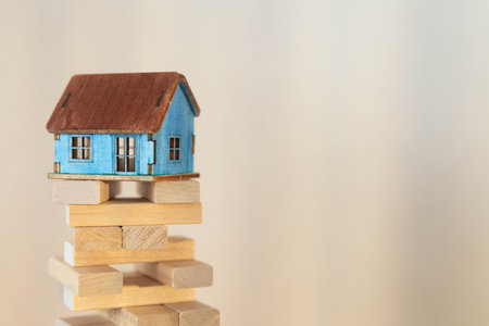 Real estate concept background. House model and coins stack on wooden table, copy space.の写真素材