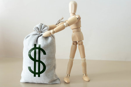 Man pulling on a rope big bag of money, gray wall on backgroundの写真素材