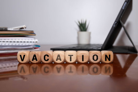 Alarm Clock with Wooden Blocks Spelling 'VACATION' Isolated on Black Background, Symbolizing Time Management Economy and Business. Wooden Blocks Displaying the Word VACATIONの写真素材