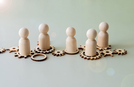 A few metal gears connected to each other and a figure of a man made of wood.の写真素材