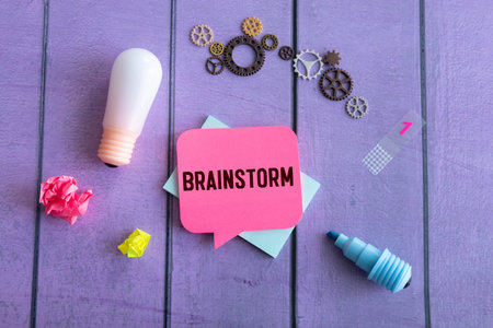 Brainstorm concept with miniature figures standing above yellow speech bubble with text brainstorm. Symbol of teamwork, idea generation, planning and problem solving.の写真素材