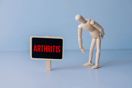 Wooden man holds his hands on sore knee isolated on white background. Concept of pain in the knee. Having knee ache. Copy space.の写真素材