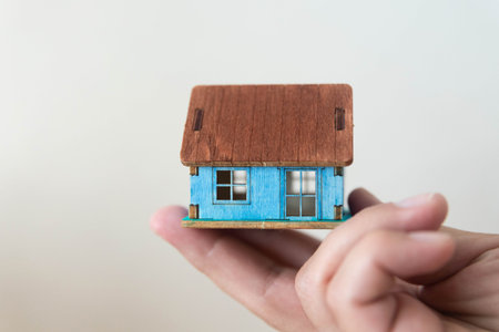 Homeless man holds a house made of cardboard in his hand