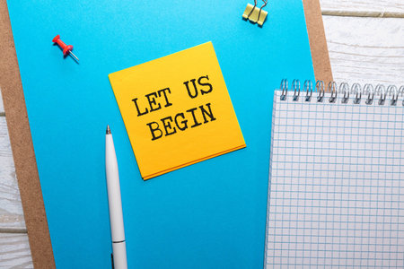 Let us begin message written on ripped torn yellow paper piece on blue background. Conceptual let us...