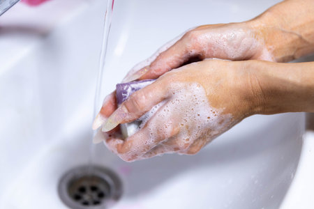 girl washes her hands with soap under running water.