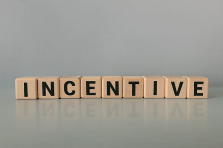 The word INCENTIVE is written on wooden cubes near the pen and document.