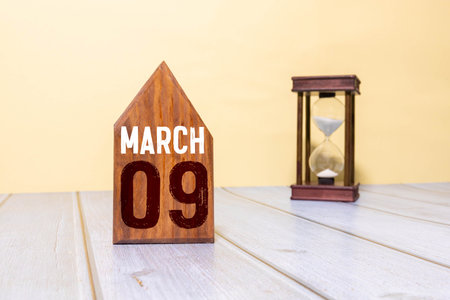 Minimalist green wooden block perpetual date calendar displaying MARCH 09 with light grey...