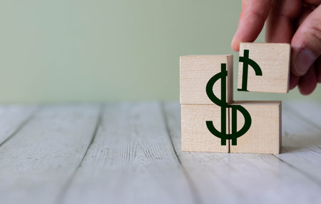 A man makes a dollar symbol out of wooden blocks.