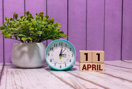 Minimalist yellow wooden block perpetual date calendar displaying APRIL 11 with light grey...