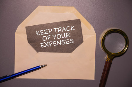 White card with the text Keep track of your expenses on wooden desk background. business concept