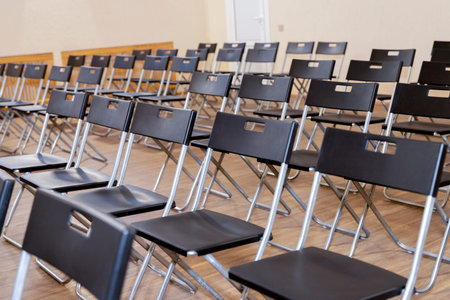 Rows of empty black folding chairs at an event