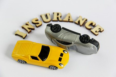 car insurance isolated on white background with wooden letters toy car crashの写真素材
