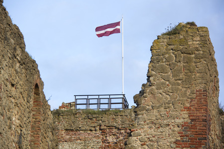 The ruins of the Livonia Order Castle was built in the middle of the 15th century. Bauska Latvia in autumn. Latvian flag on the top of the towerのeditorial素材