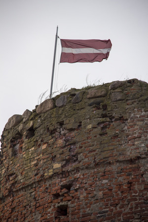The ruins of the Livonia Order Castle was built in the middle of the 15th century. Bauska Latvia in autumn. Latvian flag on the top of the towerのeditorial素材