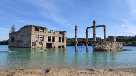 Sand Hills of Quarry With a Pond and Abandoned Prison in Rummu Estonia Europe. Flooded Houses of Former Prison. Mountain in the Abandoned Mines Sunken Ruins of Soviet Time Prison Architecture.のeditorial素材