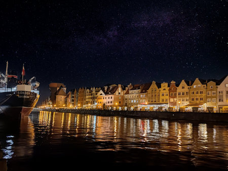 GdaÅsk Old Town - the Historical Port Crane Gate and Houses on the MotÅawa River in the Evening Time the Light Reflects in the Water the Architectural Embankment of the Baltic Port in the Evening Street of the Old Townの写真素材