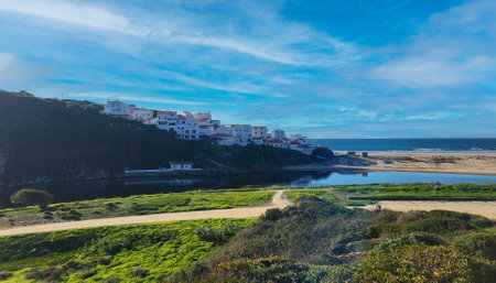 Praia De Odeceixe Mar Beach With Golden Sand, Atlantic Ocean, River Bend and White Houses of Odeceixe Village. Rota Vicentina Coast, Odemira, Portugal. Hiking Rota Vicentina the Fisherman's Trailの写真素材