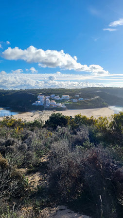 Praia De Odeceixe Mar Beach With Golden Sand, Atlantic Ocean, River Bend and White Houses of Odeceixe Village. Rota Vicentina Coast, Odemira, Portugal. Hiking Rota Vicentina the Fisherman's Trailの写真素材