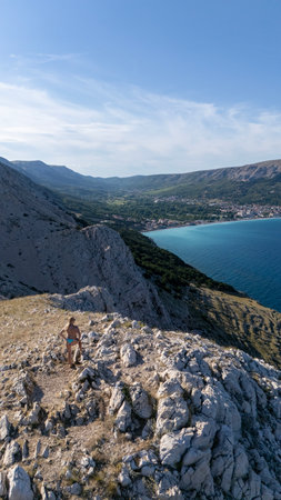 Beautiful Young Woman in Bikini Hiking Trail Leading From the Beach in Baska to the Bag Mountain Top, Panoramic Aerial Shot, Azure Water in the Bay by the Beach in Baska on Krk Island, Croatiaの写真素材