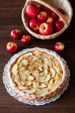 Round apple pie and red apples on brown backgroundの写真素材