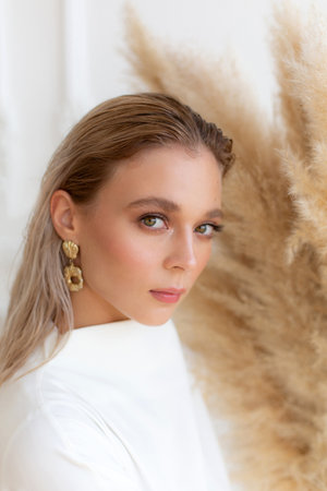 Portrait of a woman in white dress with dried pampas grass on backgroundの写真素材