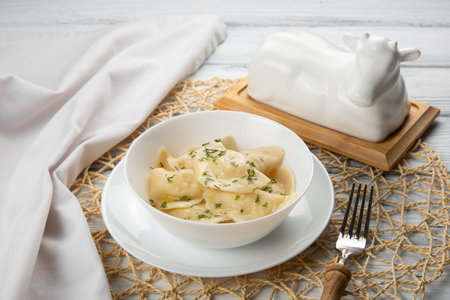 Dumplings, vareniki in white plate with napkin and white cow oilerの写真素材