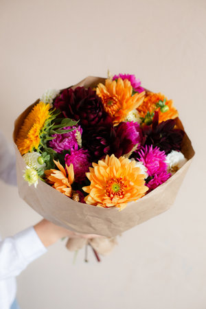 Hands holding beautiful bouquet of flowers. Hands with bouquets of seasonal flowers in craft paper.の写真素材