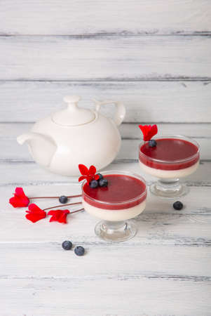Strawberry panna cotta in a glass decorated with fresh berries and flowers on white woodenの写真素材