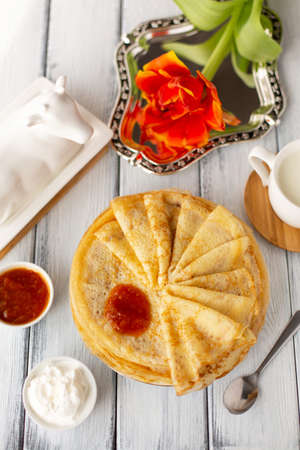 Pancakes with jam, breakfast, flower, spring, womans day. Traditional russian blini on white wooden table. Pancake week. Shrovetide. Regional food. Close up. Vertical format.の写真素材