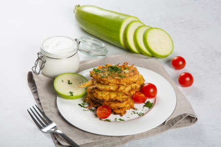 Zucchini pancakes with tomato and sour cream.の写真素材