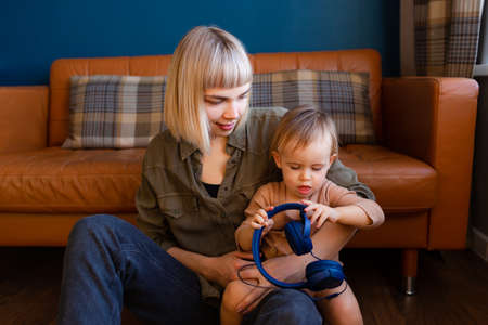 Young woman with headphones and baby at home.の写真素材