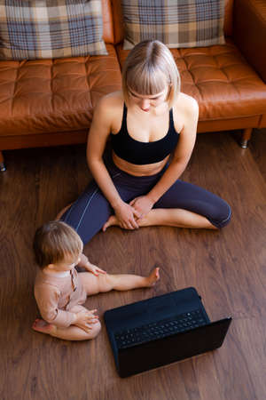 Young blond woman with child sitting on the floor at home.の写真素材