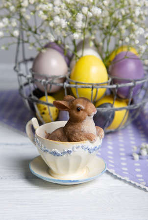 Easter bunny in cup on violet and yellow eggs on polka dot napkin.の写真素材