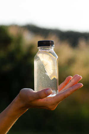 Transparent bottle with water and lemon on hand.の写真素材