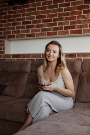 Young woman sitting on the sofa at home with telephone.の写真素材