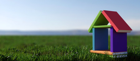 House made of colored books on green grass and blue sky.の写真素材