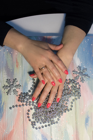 hands with neat manicure on bright background with silver-tone beads and snowflakes on wooden boardsの写真素材