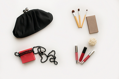 ladies clutch handbag black, set of cosmetics (lipstick, palette and brushes), a box with ornaments and jewelry on a white backgroundの写真素材