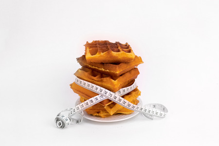 a stack of waffles on a white plate with measuring tape around them on white backgroundの写真素材