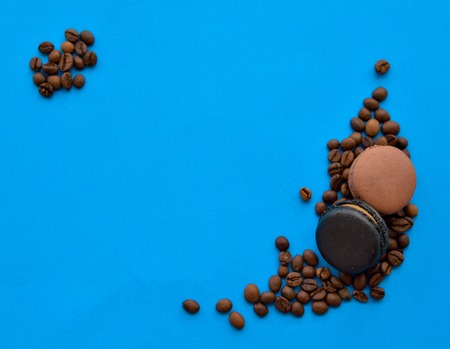 coffee beans and chocolate macaroons on a blue background with a place under the textの写真素材