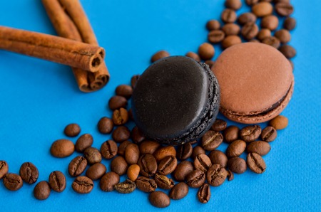 coffee beans and chocolate macaroons on a blue background with a place under the textの写真素材