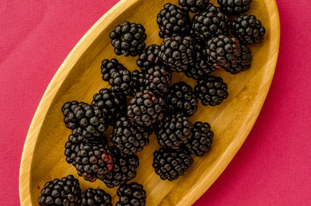 wooden plate with  berries on a pink background