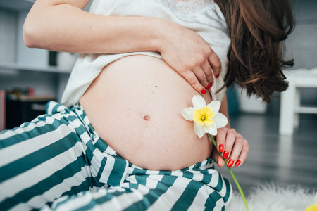 A pregnant woman hands her abdomen and yellow flower  and sonogram image daffodils