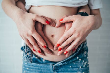 A pregnant woman hands her abdomen. A heart on the bellyの写真素材