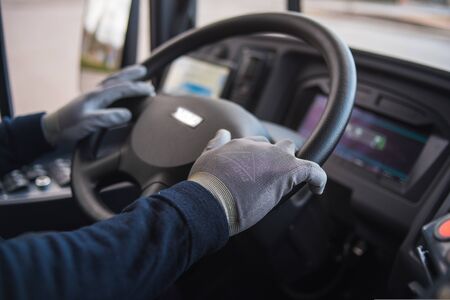 busdriver with mask puts protecting gloves on his hand in bus to protect himself from the coronavirus epidemicの写真素材