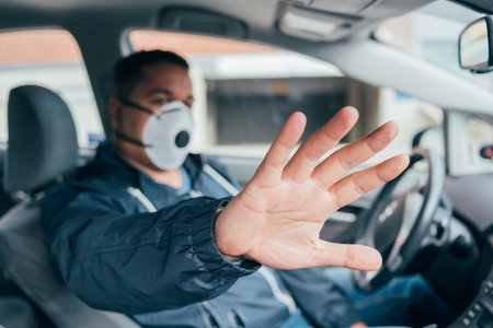 stop corona. quarantine.  covid 19. coronavirus. hand of young hispanic man, a driver of car in a protective mask. prevent  spread of coronavirus. young hispanic taxi driver stops pandemiaの写真素材