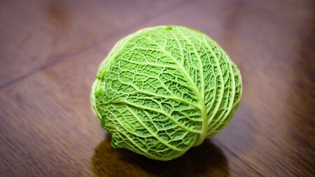 the head of green cabbage stands on a wooden tableの写真素材